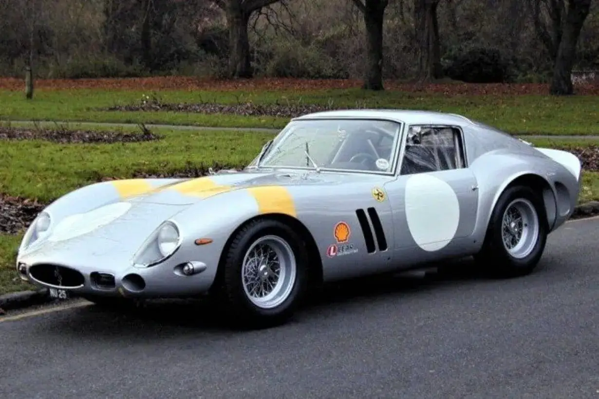 Srebrne Ferrari 250 GTO z żółtymi pasami i białymi okręgami, gotowe do wyścigu.