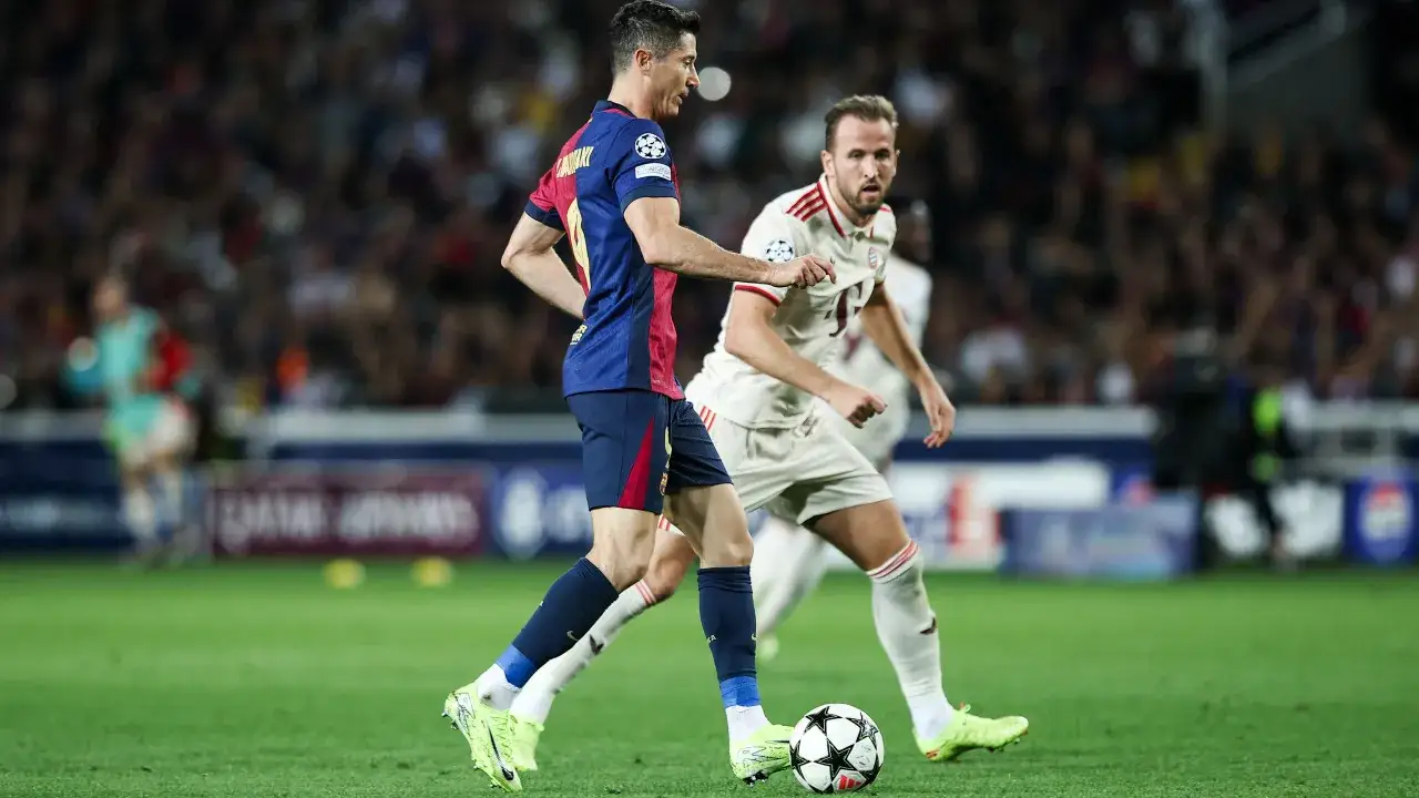 Piłkarze FC Barcelony i Bayernu Monachium walczą o piłkę. Robert Lewandowski drybluje, a Harry Kane próbuje go zatrzymać, mimo że jego **kane kontuzja** mogła go spowolnić.