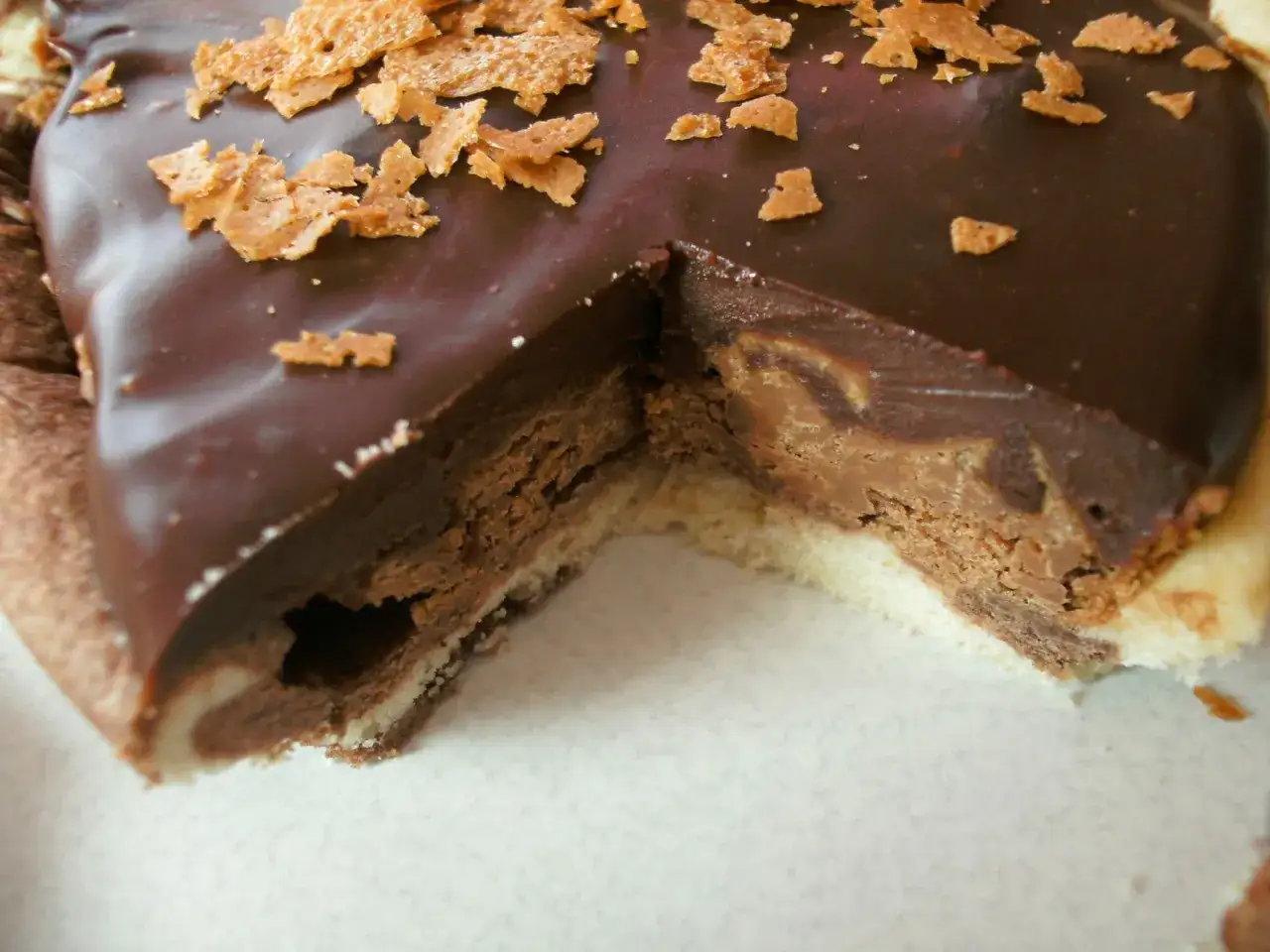 Une part de tarte au chocolat généreuse, avec une ganache onctueuse et des éclats croustillants sur le dessus.