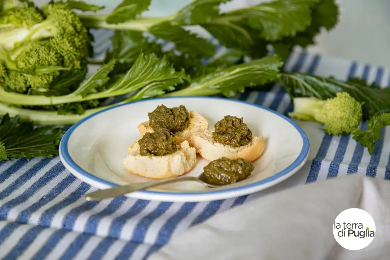 Bruschette con crema di cime di rapa, un assaggio dei prodotti DOP Puglia, con verdure fresche sullo sfondo.
