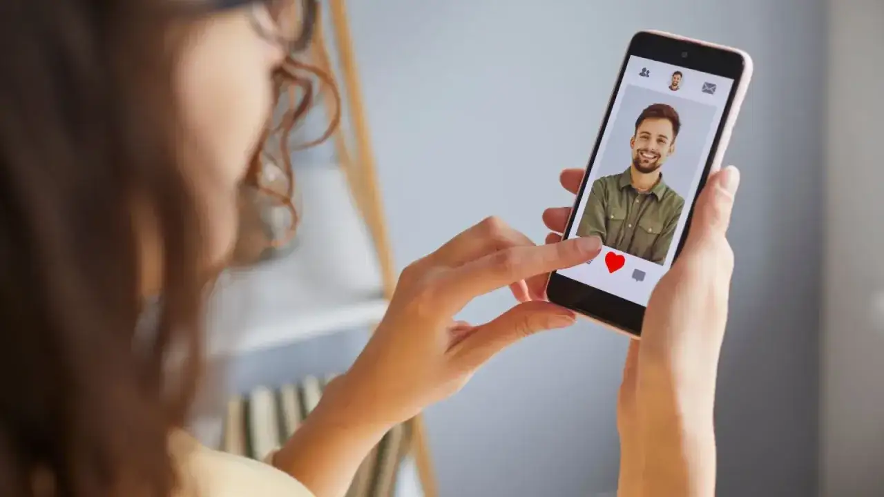Mujer desliza el dedo en un tel&eacute;fono m&oacute;vil, viendo un perfil de citas. &iquest;Ser&aacute; uno de esos perfiles falsos de Meetic?
