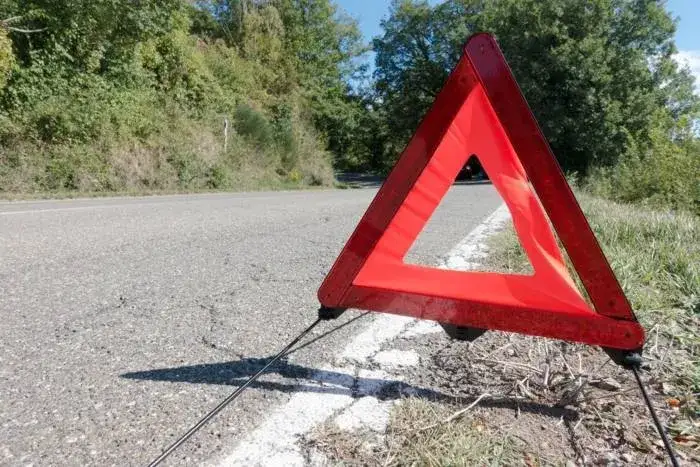 uszkodzony samochód z trójkątem ostrzegawczym stojący na poboczu drogi