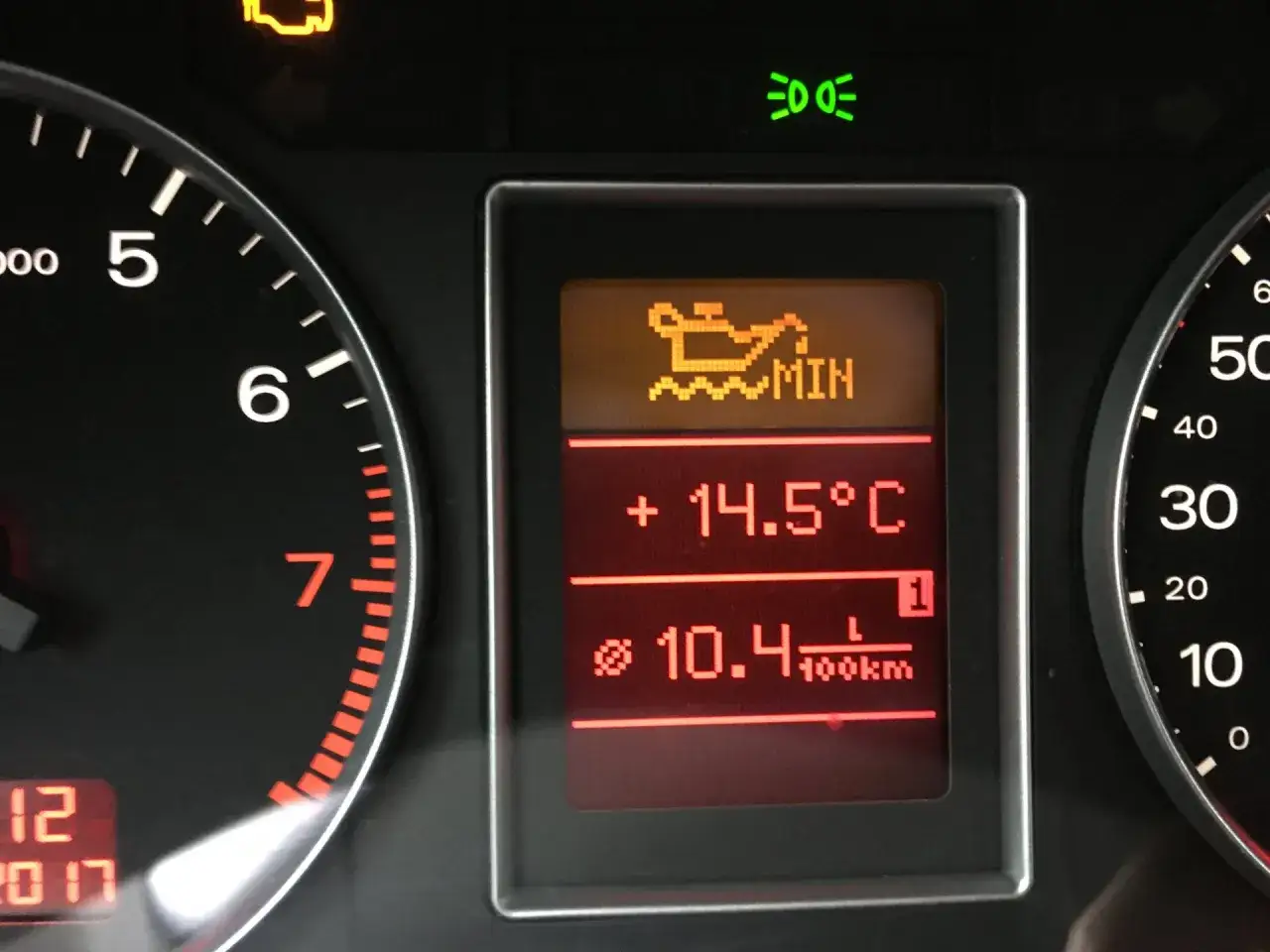 Pomarańczowa kontrolka oleju miga, sygnalizując niski poziom lub problem. Na wyświetlaczu widać też temperaturę i spalanie.