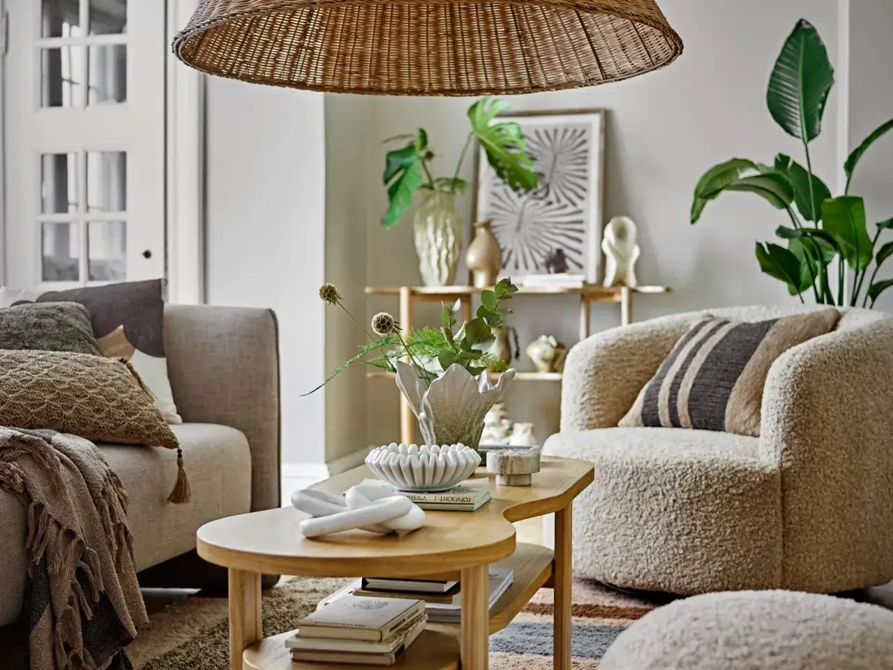 Przytulny salon w stylu minimalistycznym. Miękkie sofy, pleciony klosz lampy i naturalne materiały tworzą ciepłą atmosferę.