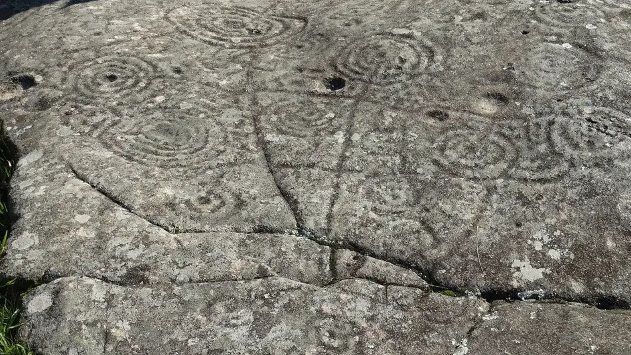 Petroglifos galicia: grabados circulares y líneas en una roca antigua, testigos de un pasado ancestral.