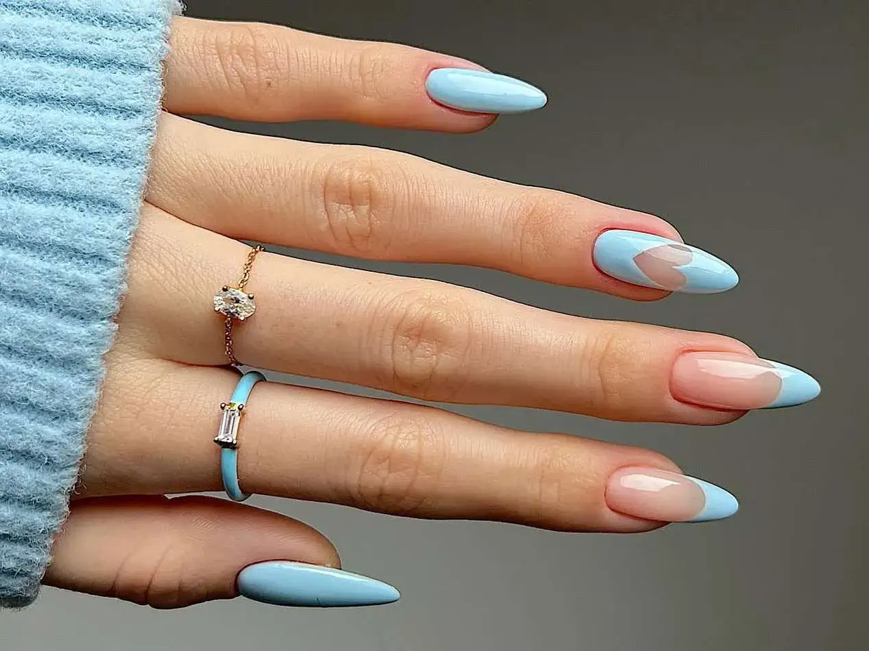 Vacker ljusbl&aring; **avril nagellack** med hj&auml;rtm&ouml;nster och fransk manikyr. Tv&aring; ringar pryder fingrarna.