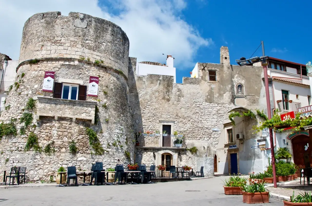 Antica torre del castello di Peschici, con tavoli all'aperto di un ristorante.