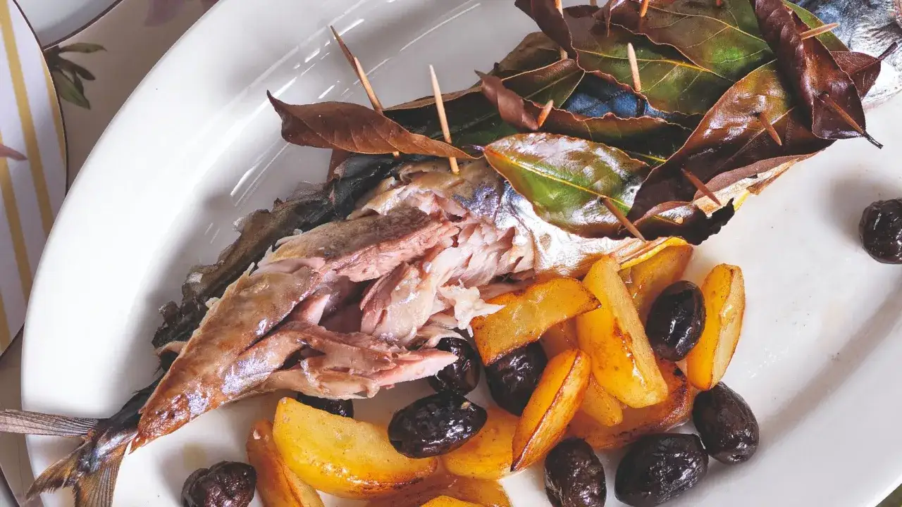 Pesce al forno con patate, olive e foglie di alloro, che ne esaltano le proprietà aromatiche e benefiche.