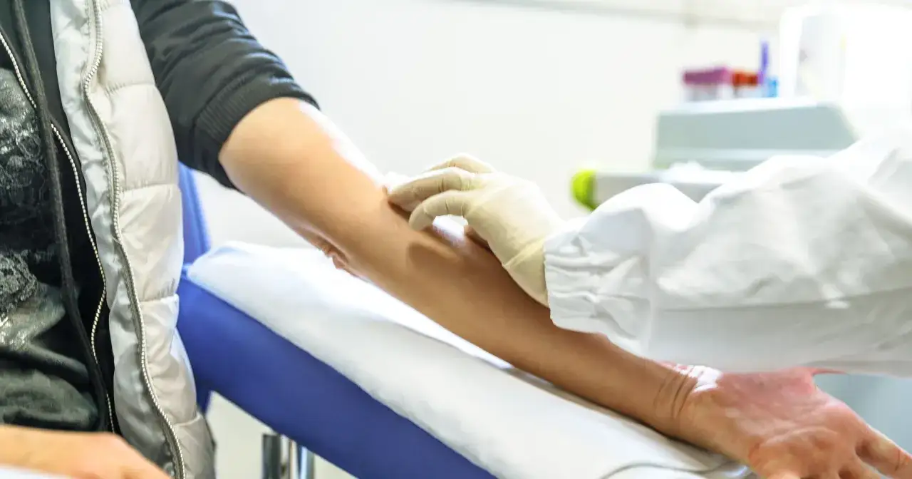 Ręka pacjenta z niskimi płytkami krwi, przygotowywana do pobrania krwi.