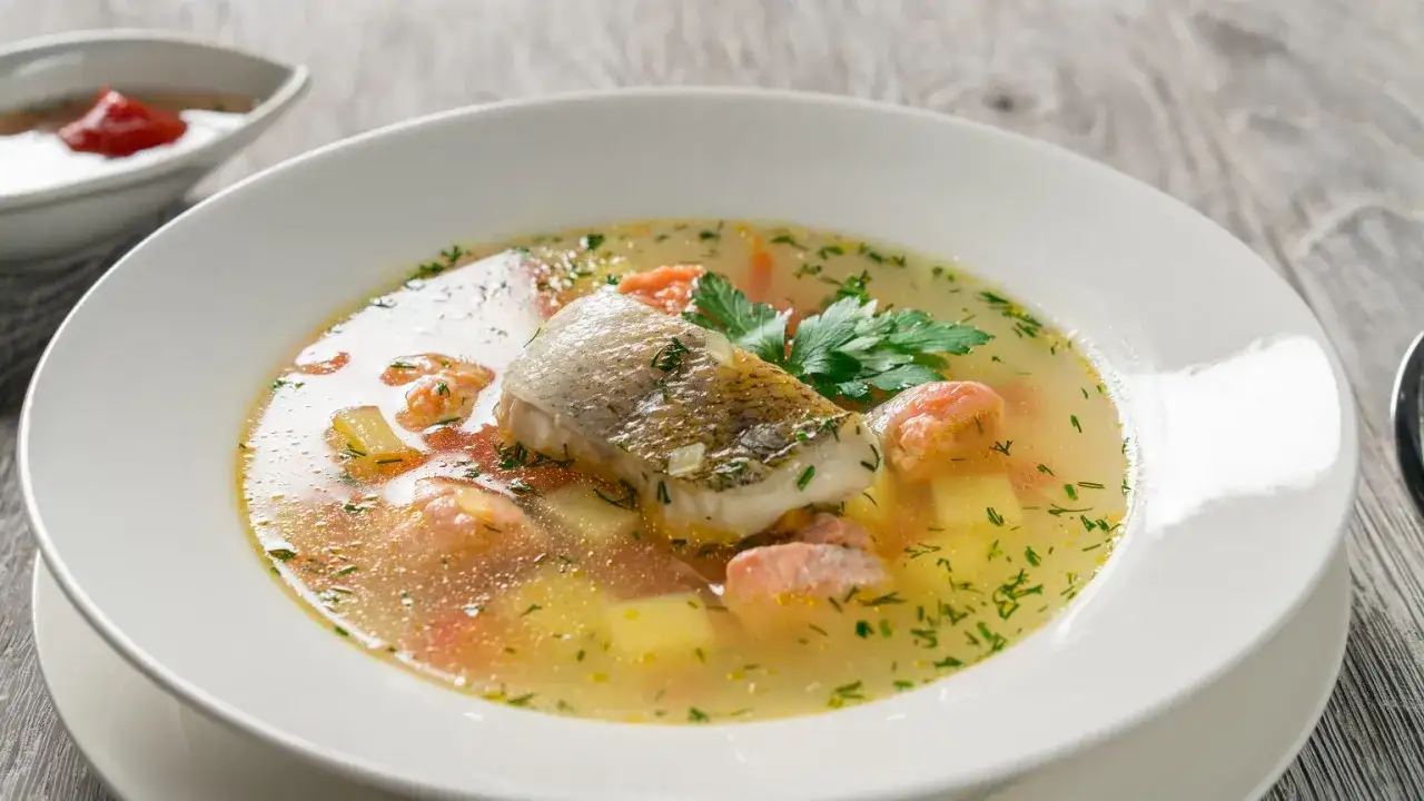 Aromatyczna zupa rybna, przepis babci, z kawałkami ryby, ziemniakami i marchewką, ozdobiona natką pietruszki.