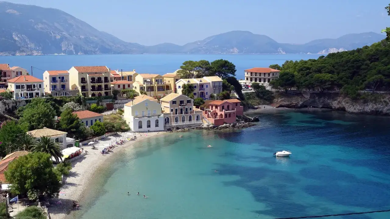 Kolorowe domy nad turkusową zatoką, plaża i góry w tle – to jedne z najpiękniejszych **kefalonia atrakcje**.