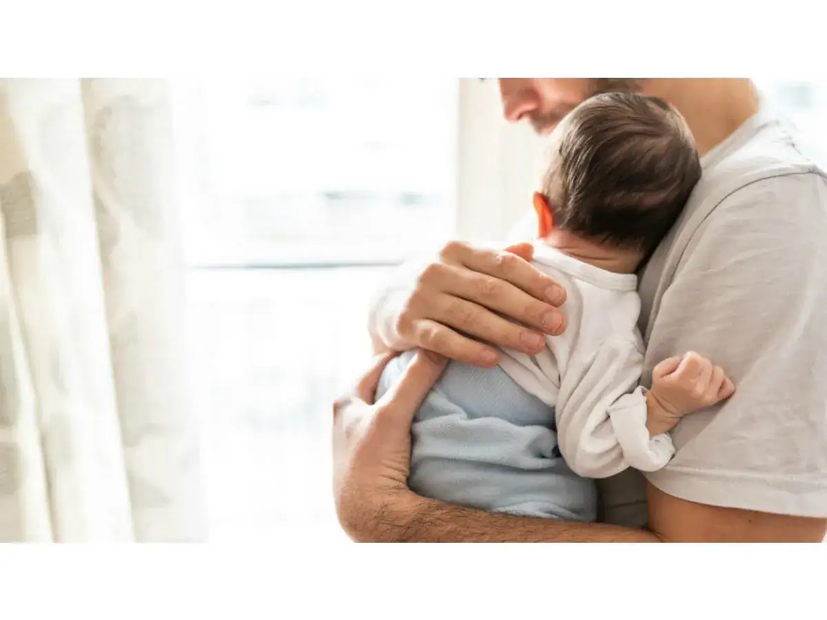 Un padre abbraccia teneramente uno dei suoi foto bimbi appena nati, cullandolo dolcemente.