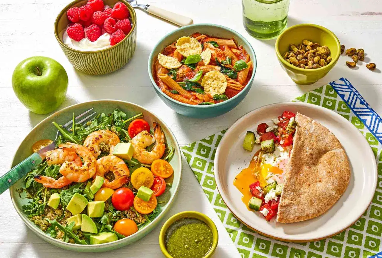 Piatto con gamberi, avocado e pomodorini, pasta al sugo, uovo con pita e yogurt con lamponi: un pasto completo che aiuta la dieta sblocca peso.