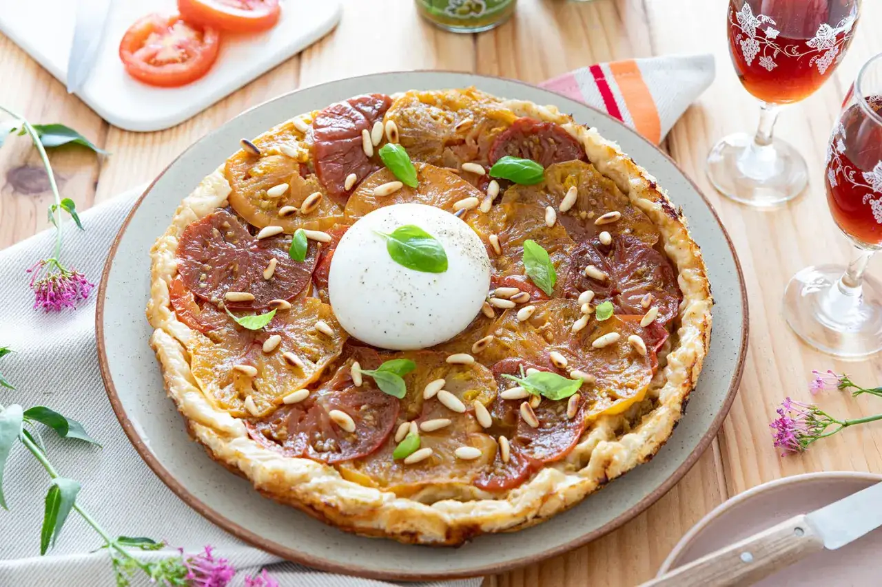 Tarte fine aux tomates multicolores, pignons de pin et burrata crémeuse. Un accompagnement tarte tomate parfait pour un repas estival.