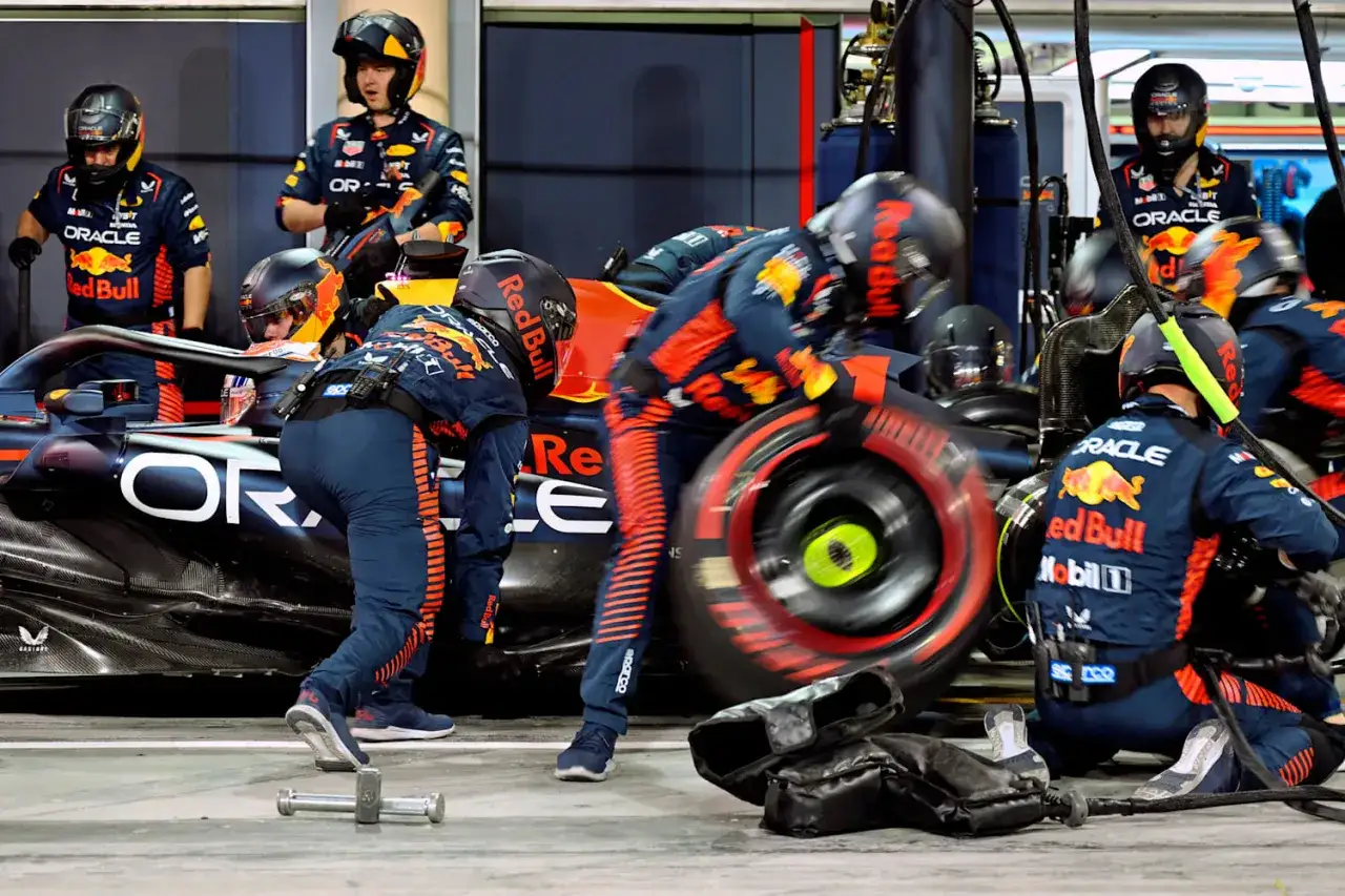 Equipo de Red Bull F1 en boxes, cambiando una rueda a gran velocidad.