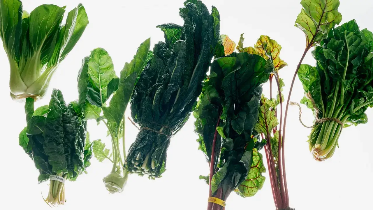 Variedad de verdura fresca, incluyendo bok choy, col rizada y acelgas, listas para una comida saludable.