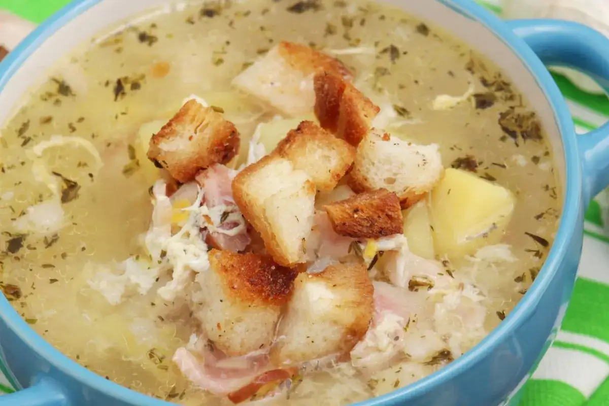Pyszna zupa na rosole z kawałkami kurczaka, ziemniaków i chrupiącymi grzankami.