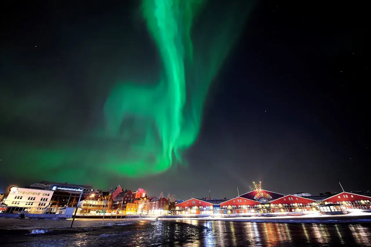 Norrsken över Luleå med sina röda byggnader och vattenspeglingar. En magisk natt.
