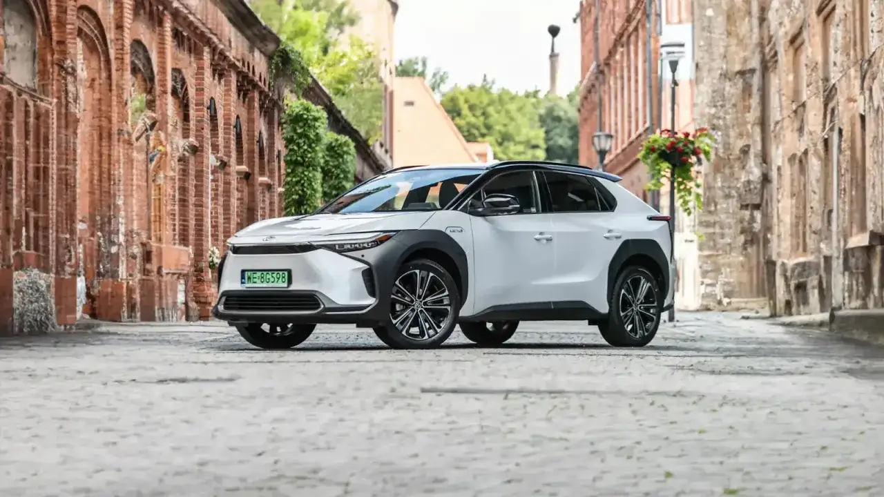 Biała Toyota bz4x na brukowanej uliczce. Ten elektryczny SUV zachwyca swoim nowoczesnym designem i imponującym zasięgiem, idealny na miejskie podr&oacute;że i dalsze wyprawy.