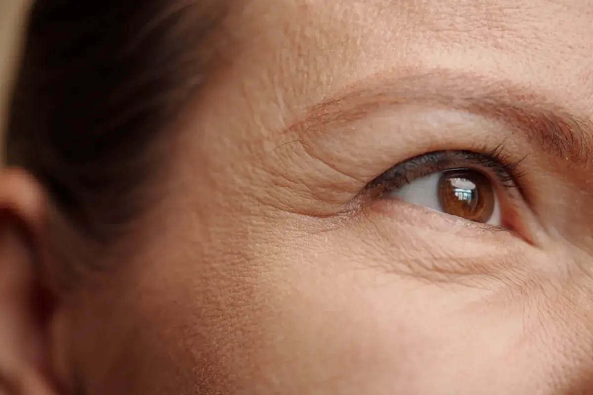 Primer plano del ojo de una persona, mostrando arrugas estáticas alrededor del párpado y la piel.