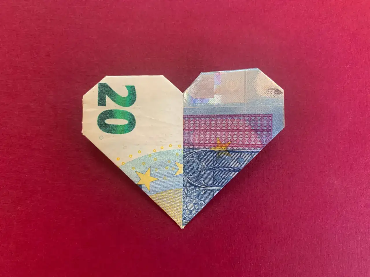 Origami-Herz aus 20-Euro-Schein, kunstvoll gefaltet. Geld formen kann Liebe zeigen.