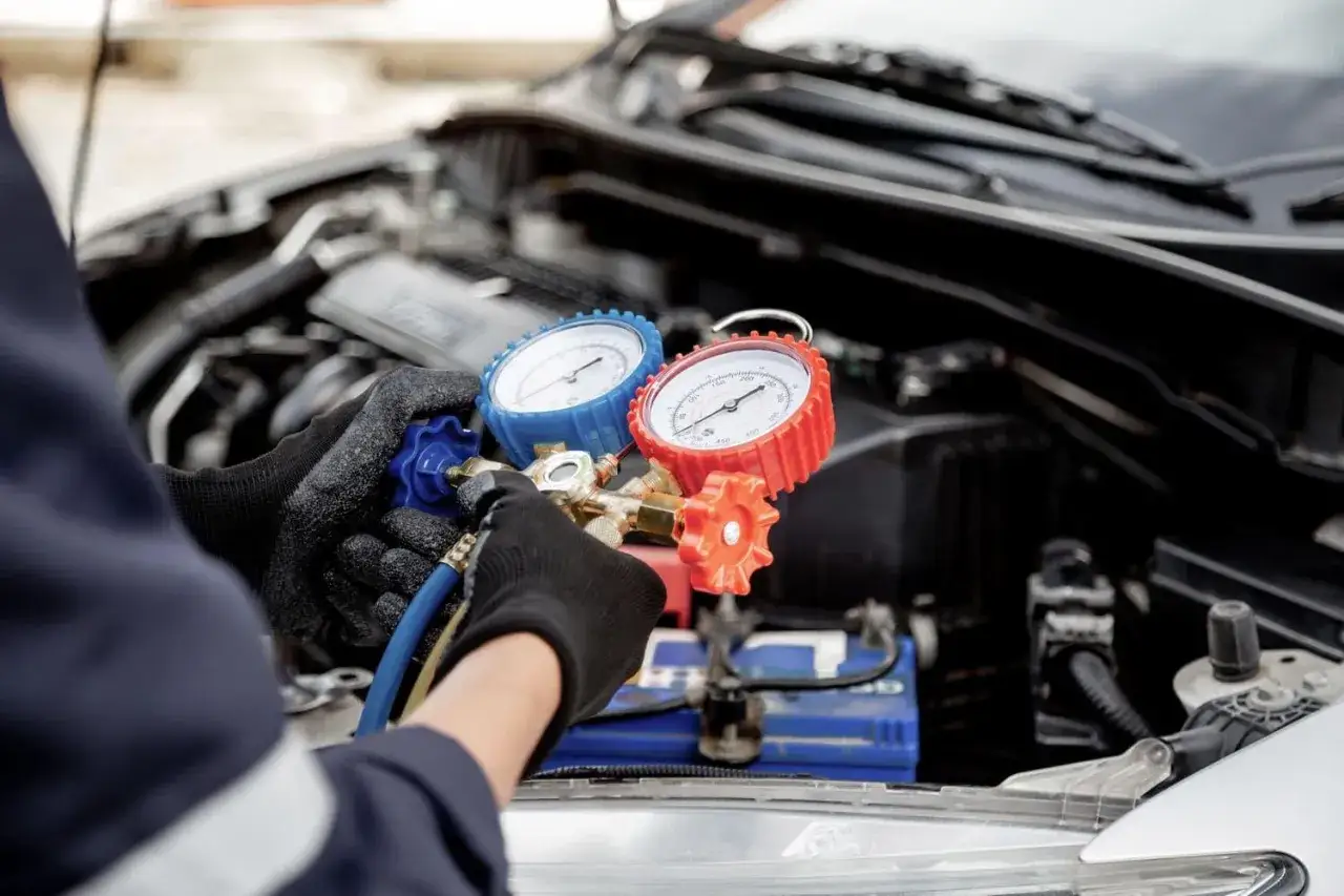 Mechanic checks car AC with gauges. Wondering how much to fix AC in car? This diagnostic tool helps determine the issue.