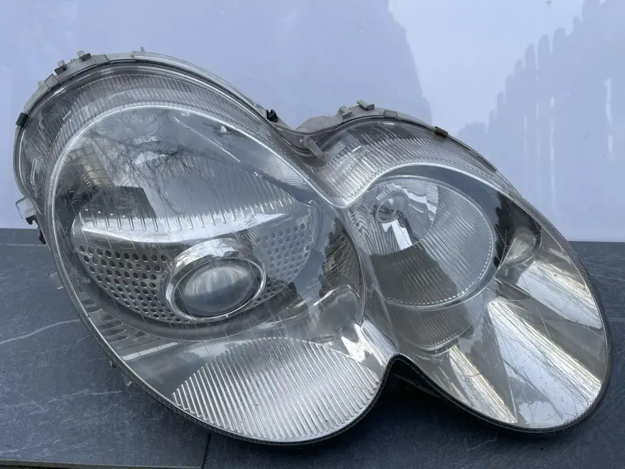 Przednia lampa samochodowa, przygotowana do montażu ksenonów. Przezroczysty klosz z wyraźnymi przetłoczeniami.