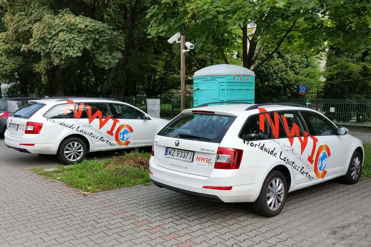Dwa białe samochody z logo firmy i napisem 