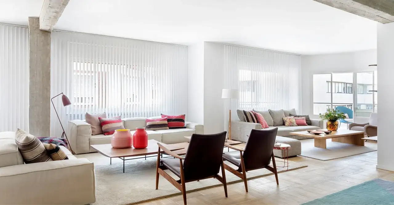 Sal&oacute;n moderno con sof&aacute;s blancos y grises, mesas de centro de madera y alfombras. &iquest;Cu&aacute;nto cuesta reformar una casa de 150 metros?