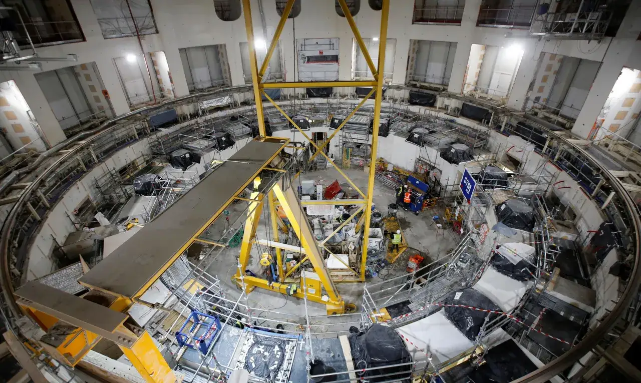 Budowa reaktora jądrowego Westinghouse. Wnętrze obiektu z rusztowaniami, dźwigami i pracownikami.
