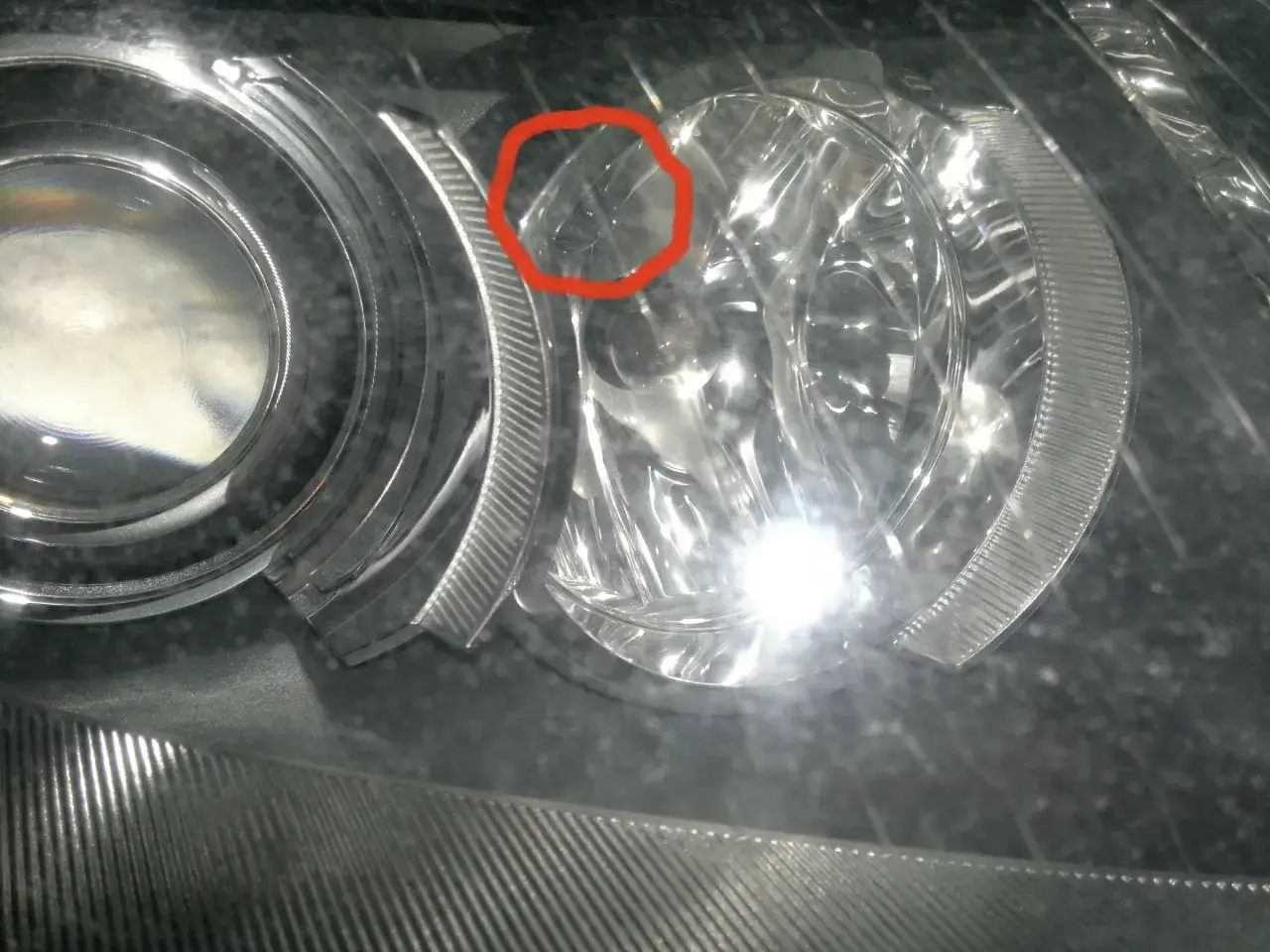 Reflektor Audi A6 C6, widoczna mała rysa na kloszu.