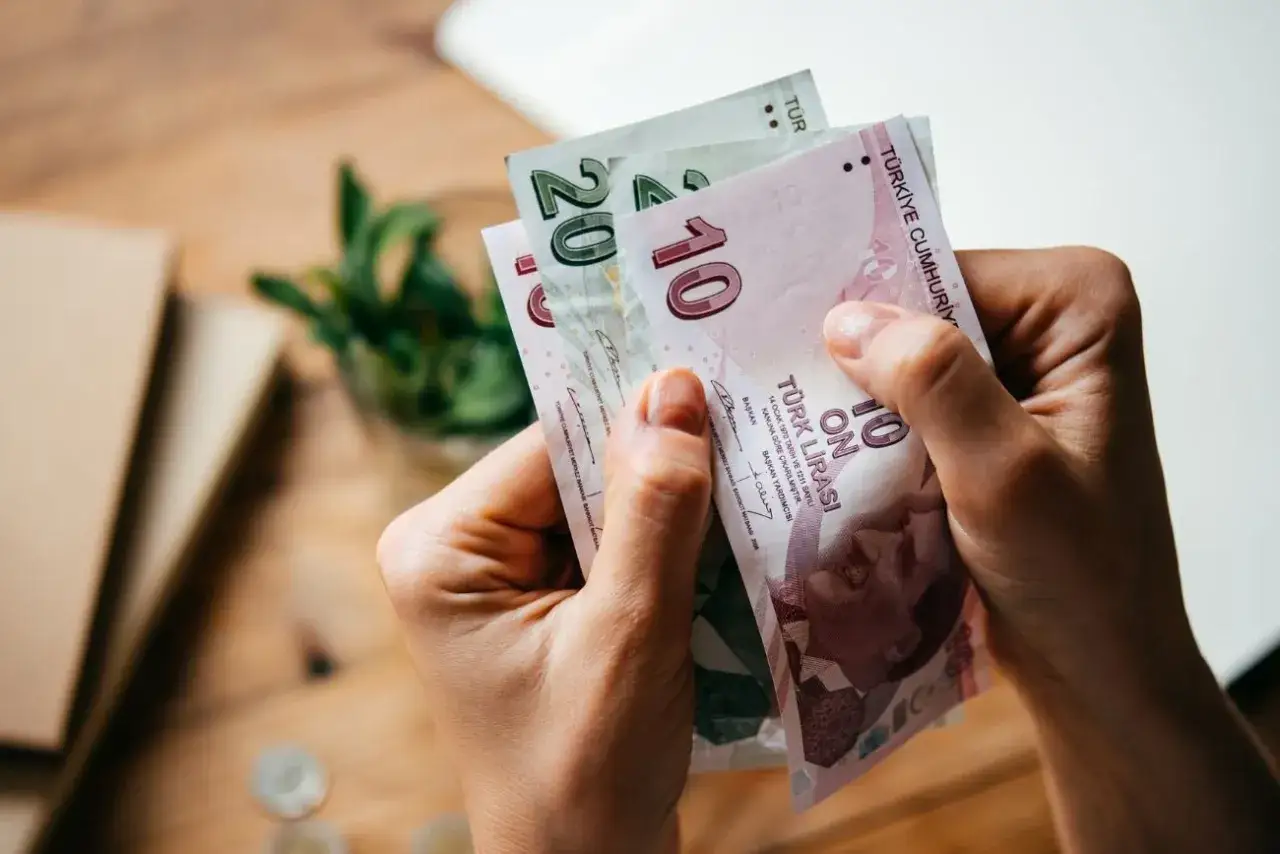 Ręce trzymają banknoty liry tureckiej. Pytanie, czy w Turcji można płacić dolarami, pozostaje otwarte, ale te banknoty pokazują lokalną walutę.