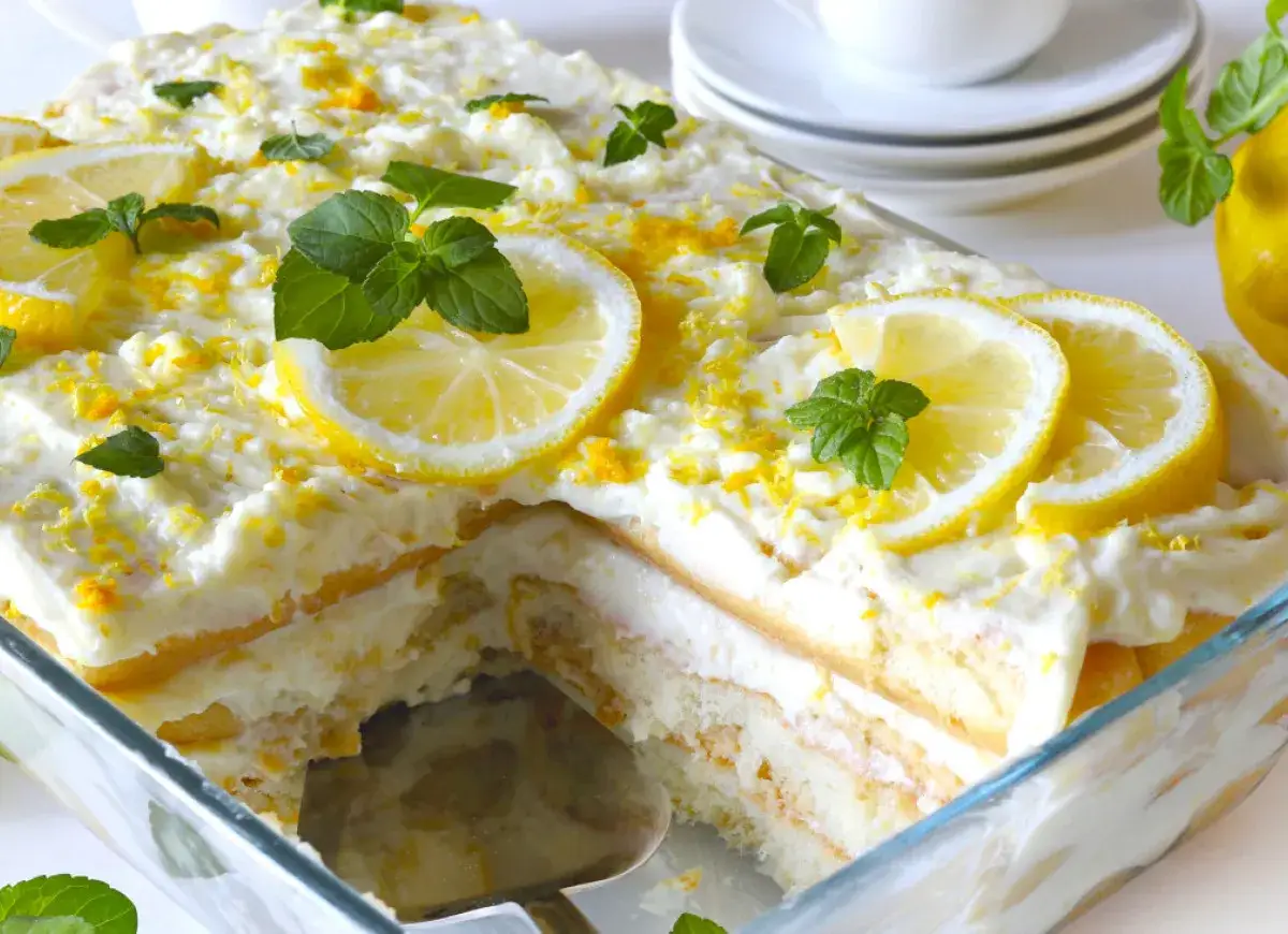 Pyszne tiramisu cytrynowe w szklanej formie, udekorowane plasterkami cytryny i listkami mięty.
