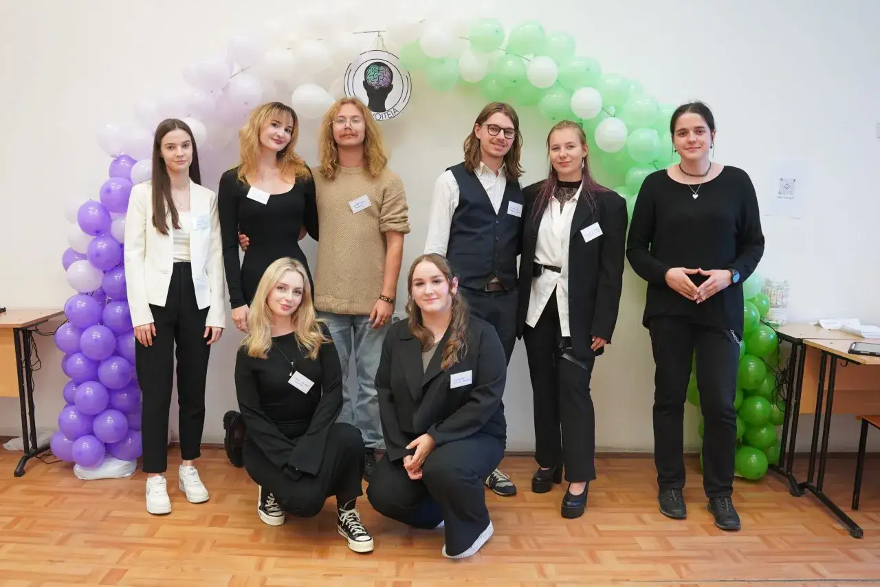 Grupa młodych ludzi, którzy chcą dowiedzieć się, jak zostać psychologiem, pozuje na tle balonów.