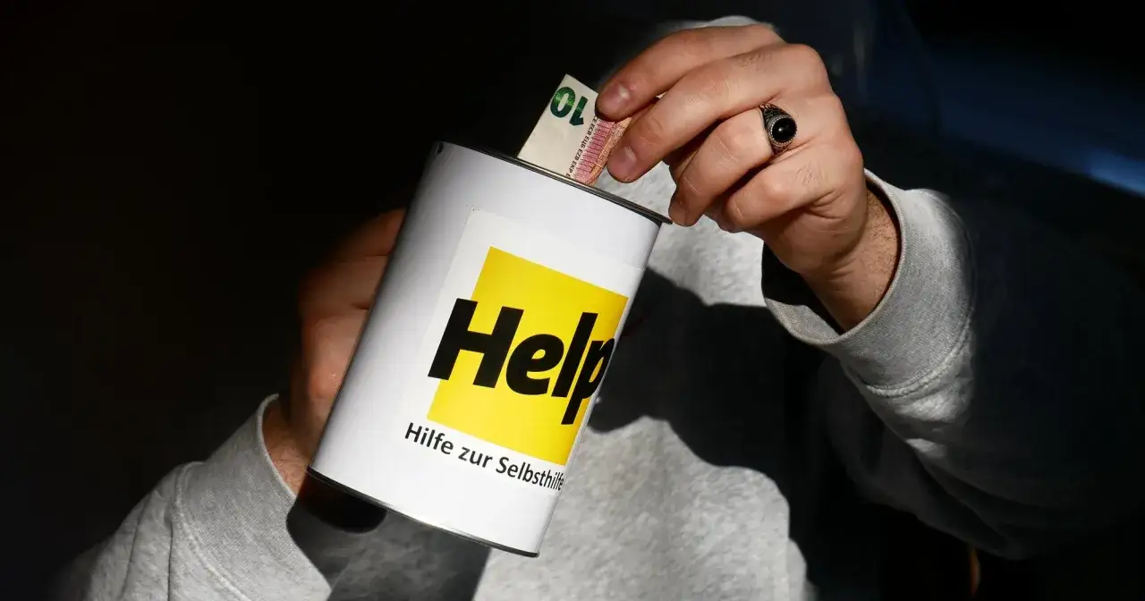 Hände legen Geld in eine Spendenbüchse mit der Aufschrift