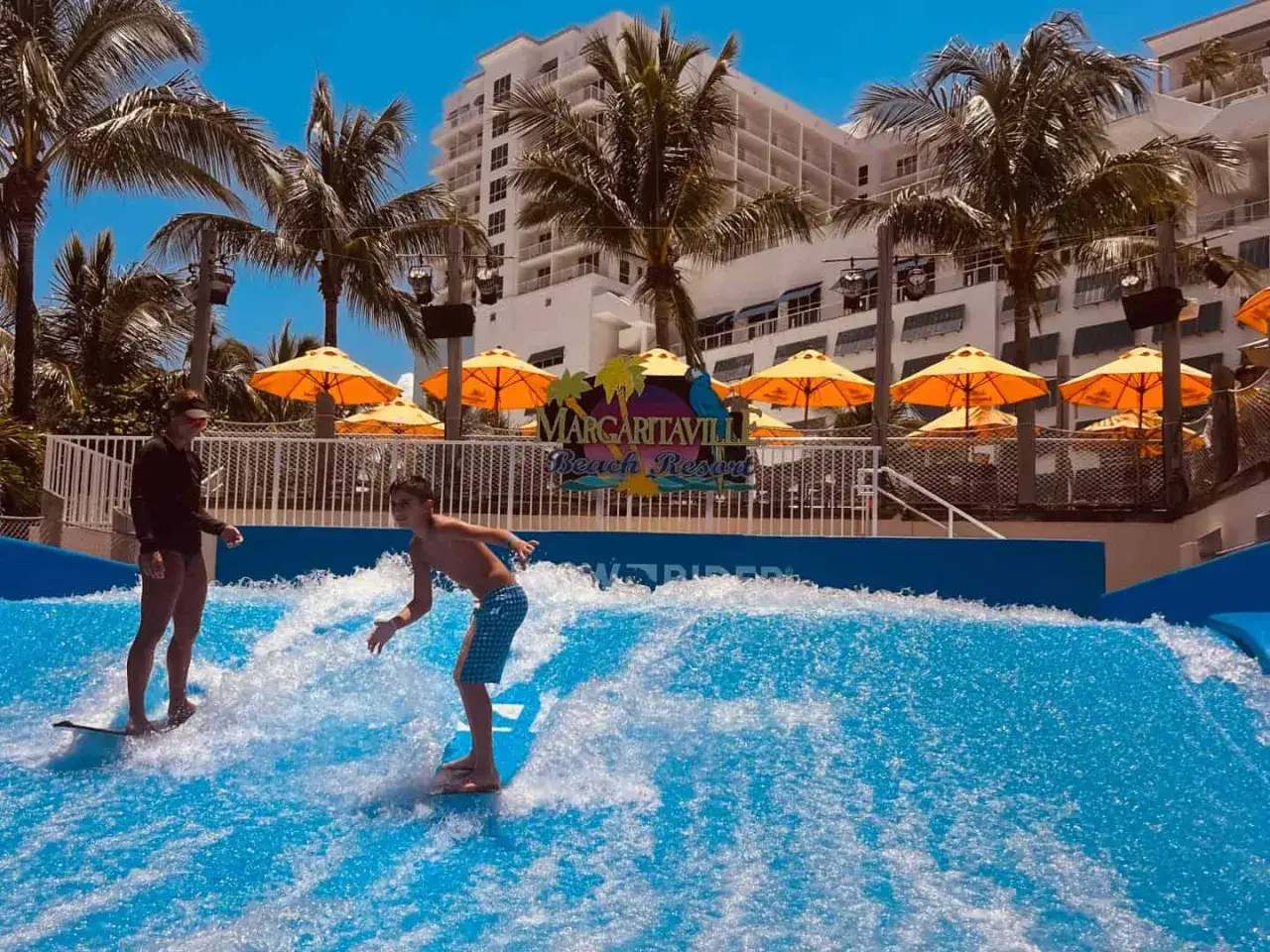 Dzieci bawią się na sztucznej fali w resorcie Margaritaville Beach. Rodzinna, ekologiczna zabawa na wodzie.