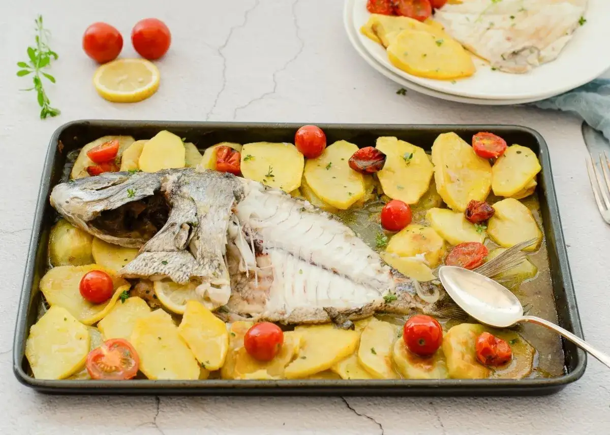 Pargo al horno con patatas y tomates cherry, listo para servir.