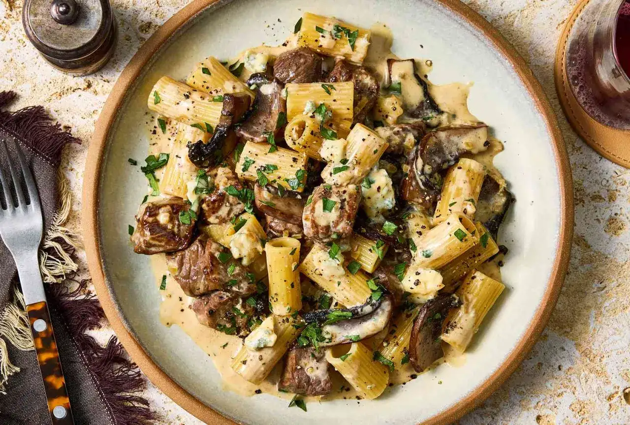 Herzhafte Rigatoni mit zarten Fleischstücken und Pilzen in cremiger Gorgonzola-Sauce, garniert mit Petersilie.