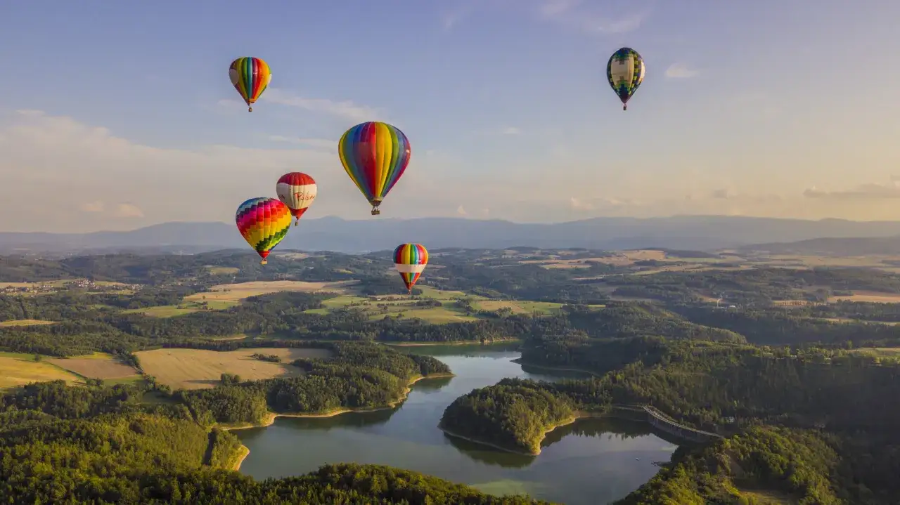 Kolorowe balony unoszą się nad malowniczym krajobrazem. Zastanawiasz się, ile kosztuje lot balonem? To niezapomniane przeżycie!