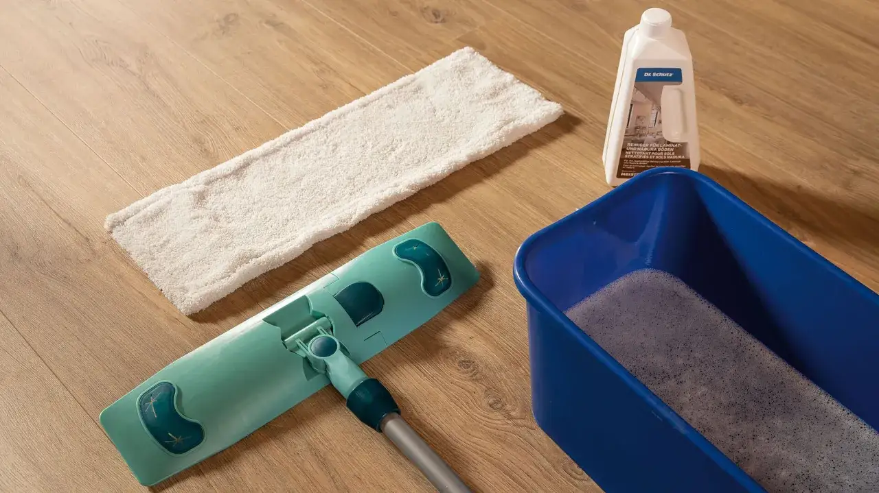 Mopp, Eimer mit Schaum und Reinigerflasche bereit, um den Designboden zu reinigen.