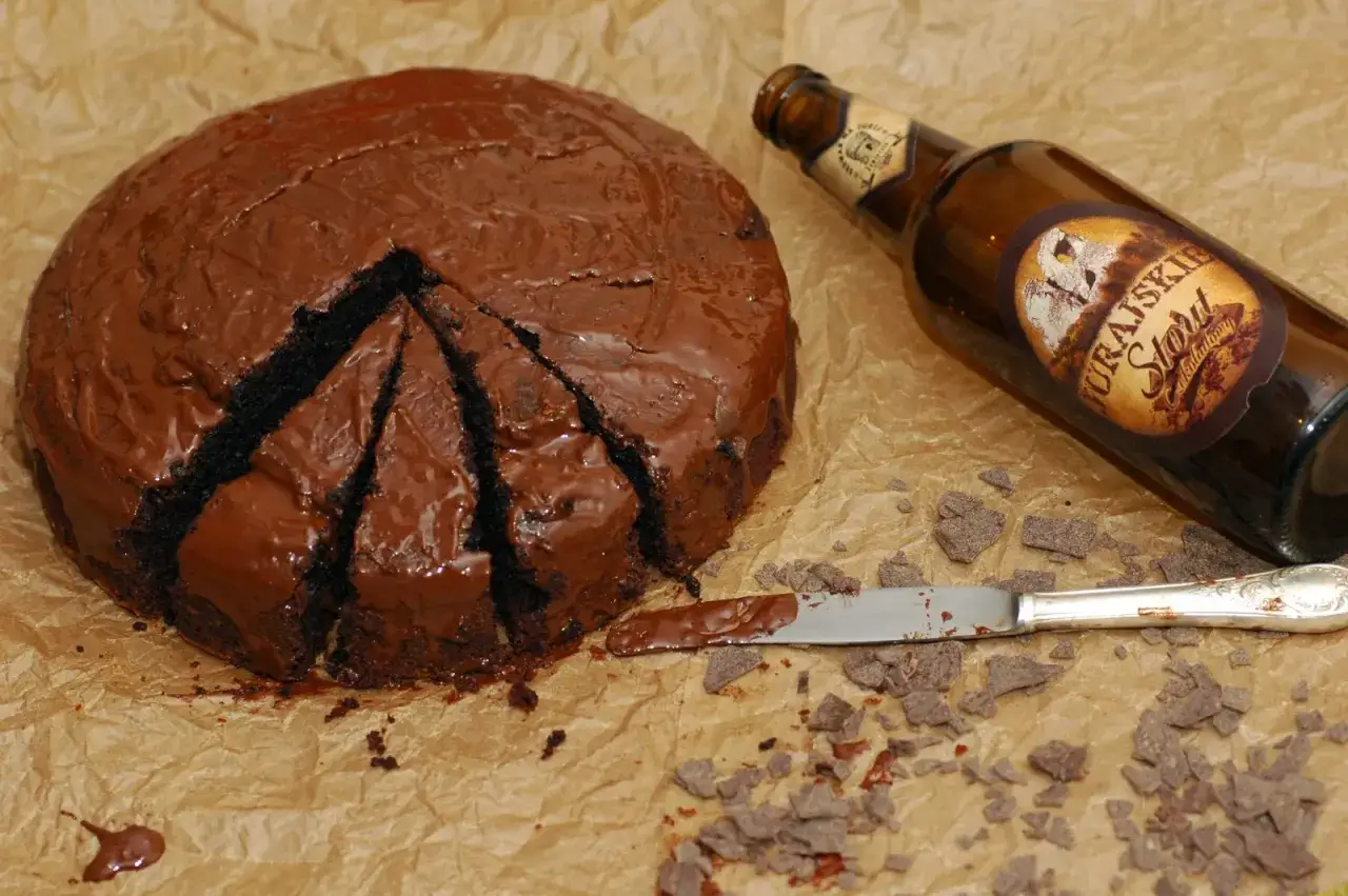 Czekoladowy tort, pokrojony na kawałki, obok butelka piwa. Idealny przepis na to, jak zrobić tort z piw.
