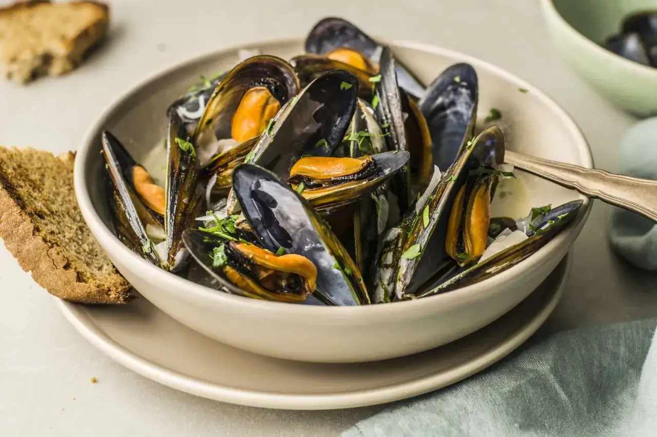 Schmackhafte Muscheln in einer Sch&uuml;ssel, garniert mit Petersilie. Perfekt f&uuml;r Muscheln essen Rezepte mit Brot.