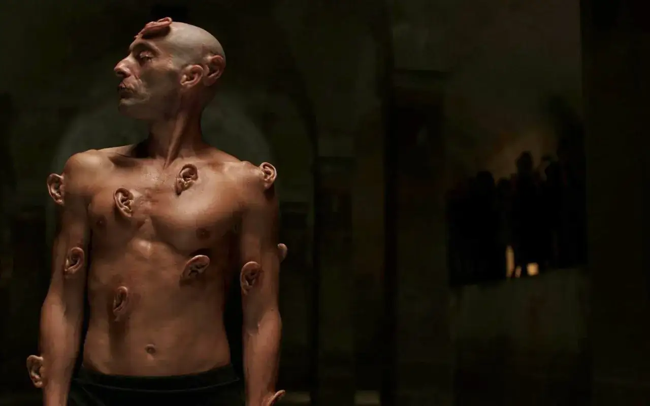 Uomo con orecchie innestate sul corpo, un'immagine che evoca il **videodrome significato** di trasformazione e ossessione mediatica.