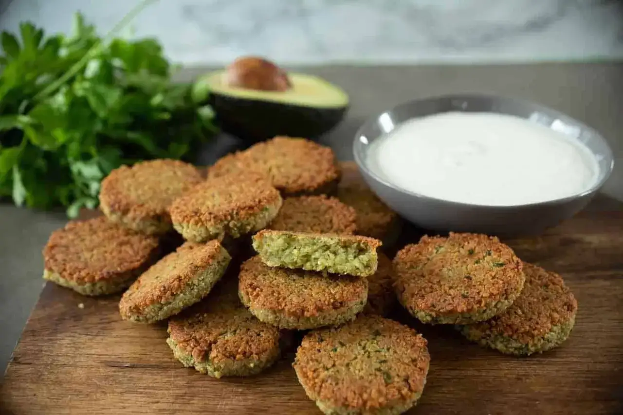Leckeres Falafel Rezept: goldbraune Falafel auf Holzbrett, dazu Tahini-Dip, Avocado und frische Petersilie.