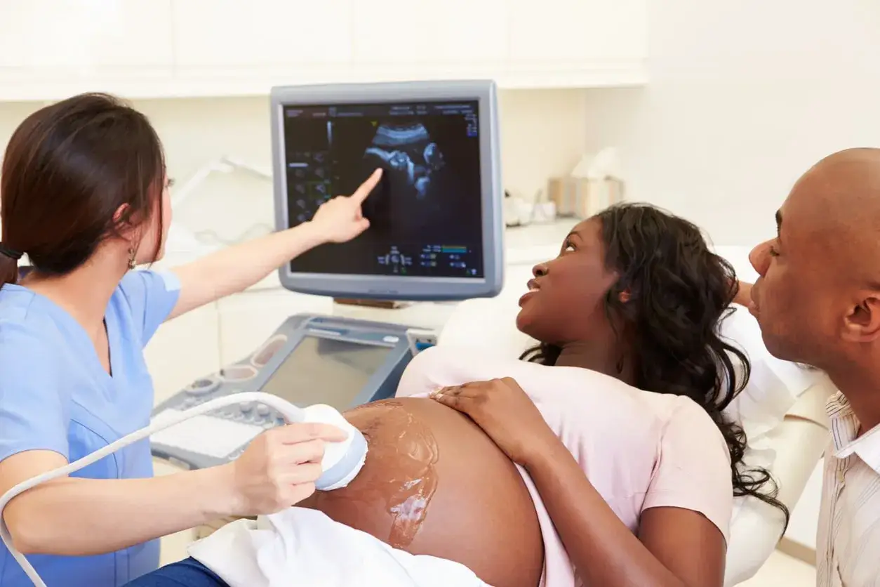 Ecograf&iacute;a de una mujer embarazada, con su pareja observando. La doctora se&ntilde;ala la imagen en pantalla, mostrando el progreso del embarazo, incluso tras endometriosis.