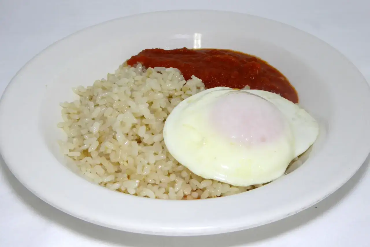 Un plato de arroz a la cubana con huevo frito y salsa de tomate.