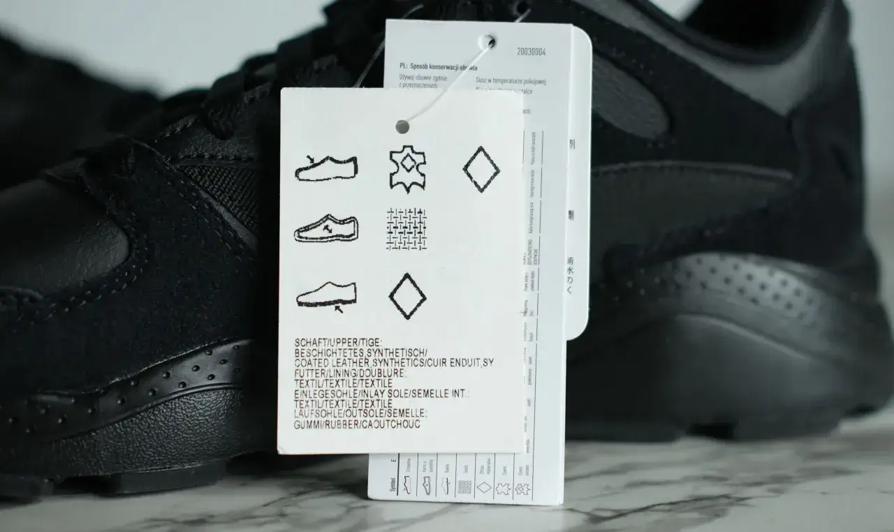 Czarne buty sportowe, których materiał syntetyczny jest widoczny na metce.