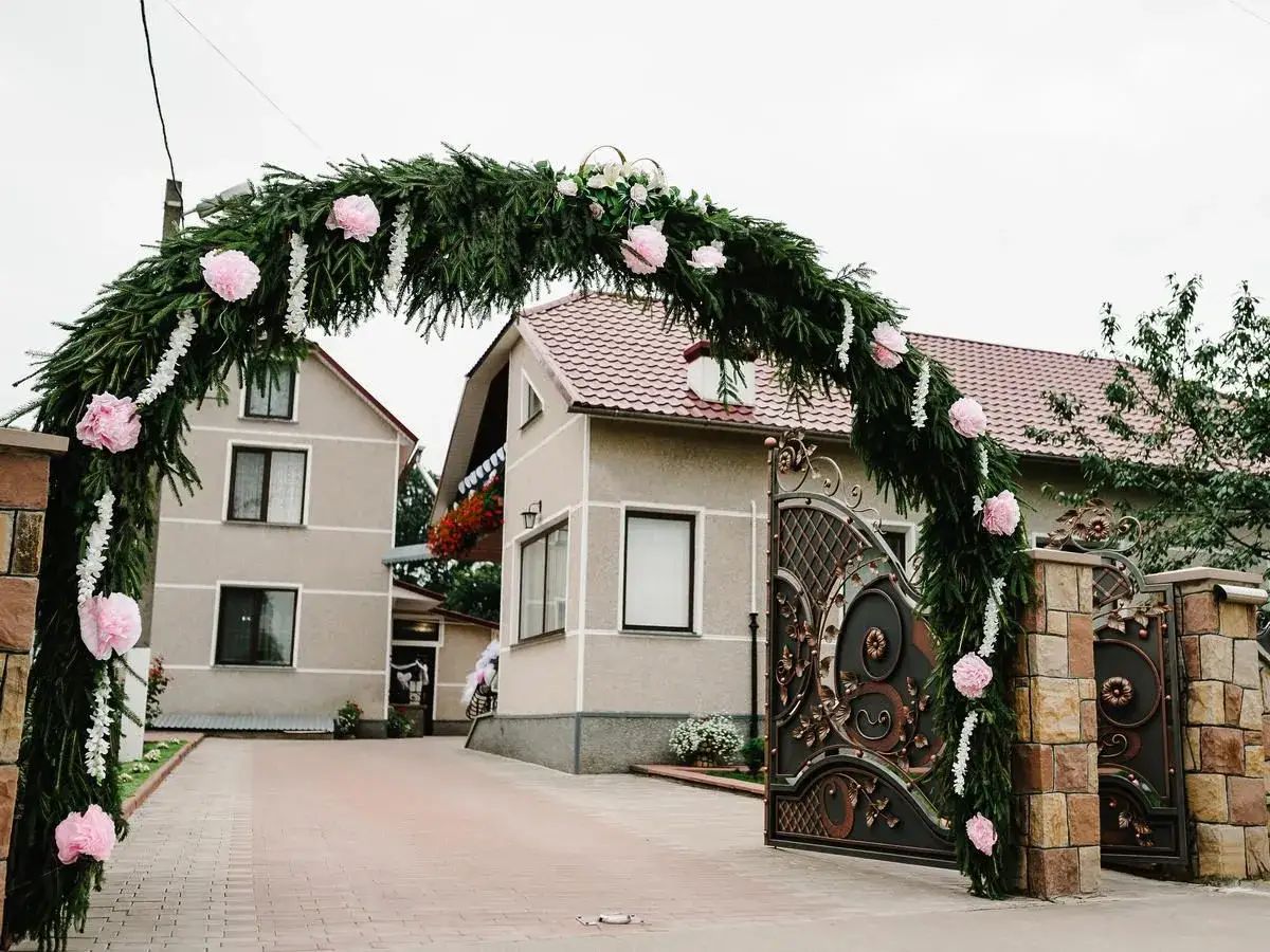 Zielona brama weselna z różowymi kwiatami. Tradycje bram weselnych i rola gości w ich tworzeniu.