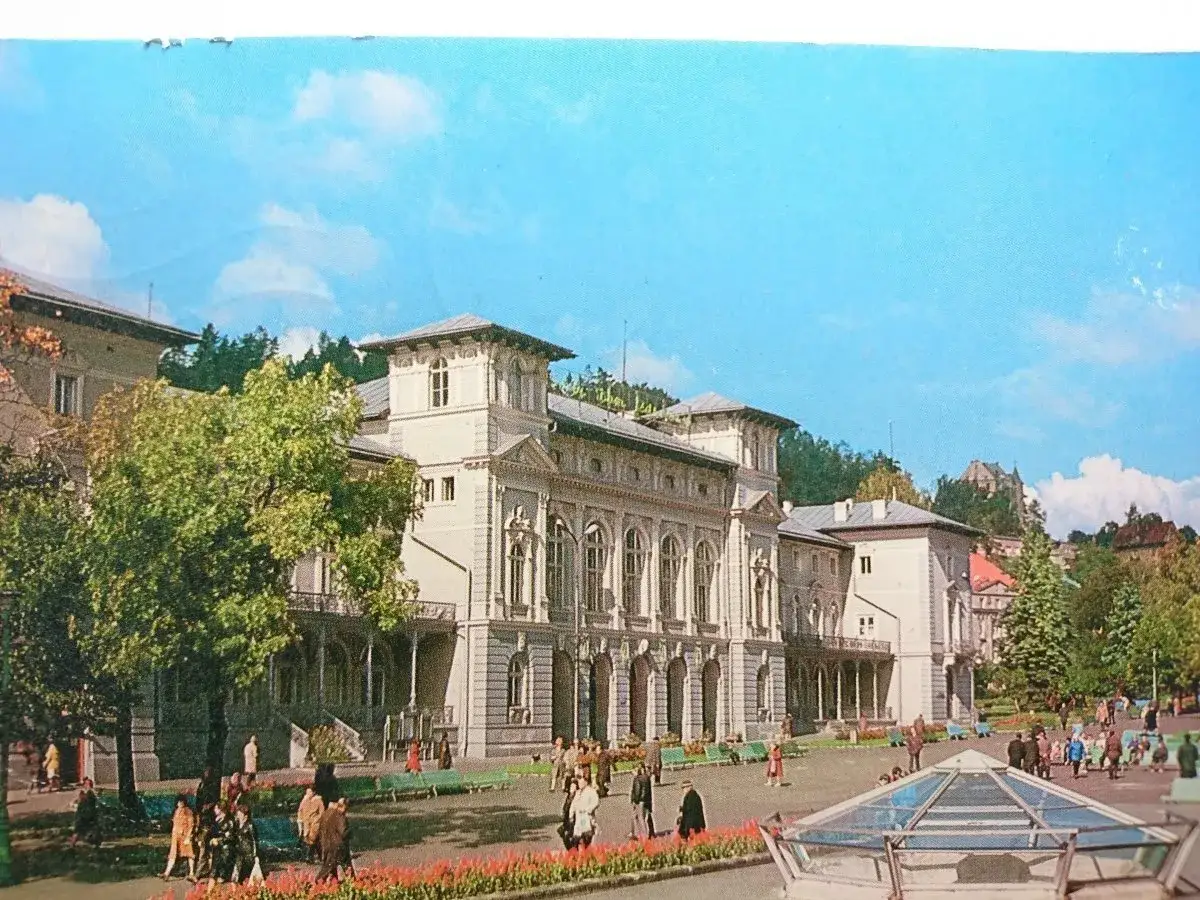 Elegancki budynek w Krynicy-Zdroju, z ludźmi spacerującymi pośród zieleni i kwiatów. Wspaniałe krynica-zdrój atrakcje.