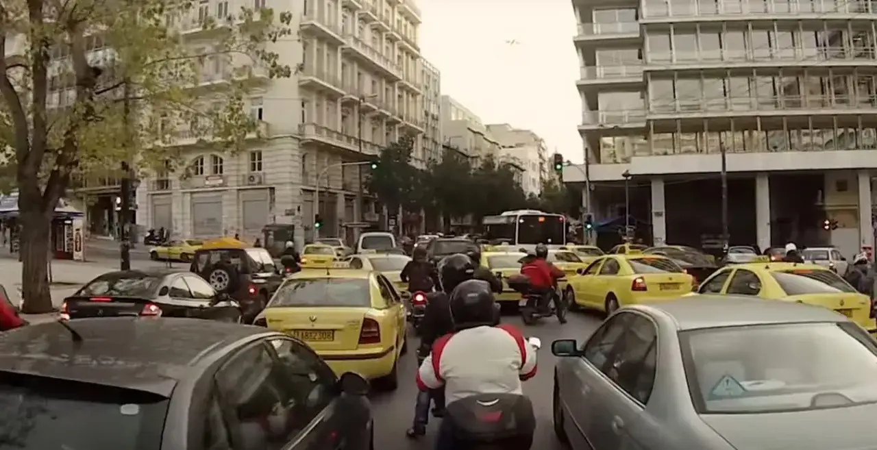 Busy Athens street with many yellow taxis and motorcycles. Considering the traffic, should I rent a car in Athens?